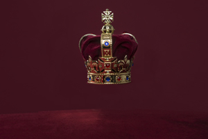 English Royal Crown on a velvet cushion on a deep red background