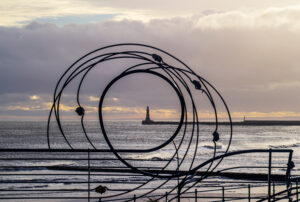 Art sculpture framing Roker Lighthouse on the coast of Sunderland, England